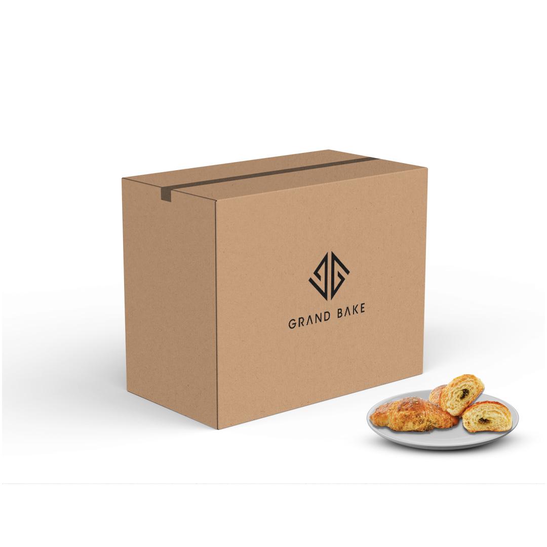 A cardboard box with 'GRAND BAKE' logo on it contain croissant zaatarof 60gm*70pcs placed next to a plate with some croissants.