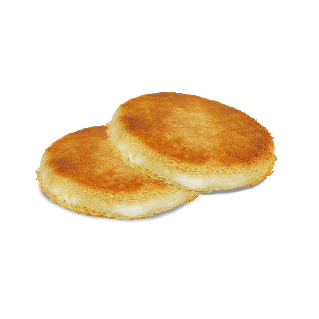 Two round Kunafa frozen cream pastries with a golden-brown surface and a white frosting-like topping on a white background.